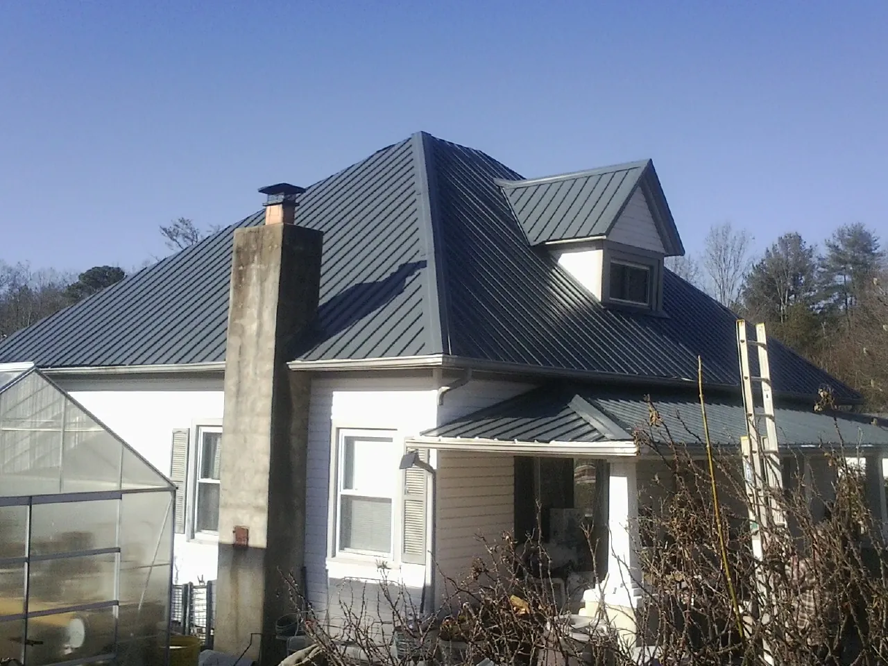 Dark blue standing seam metal roof on a white farmhouse with dormer — Slate & Tile Roof Repair by Roofing Brothers in Shapleigh