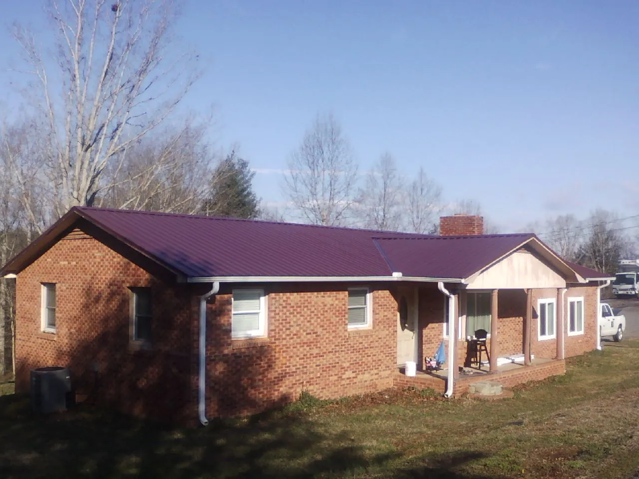 Burgundy metal roof on a brick ranch home with a new addition in Shapleigh