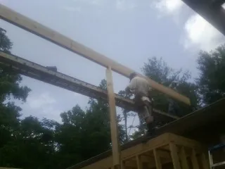 Carpenter setting a ridge beam over a new addition frame — Ice Dam Removal by Roofing Brothers in Shapleigh