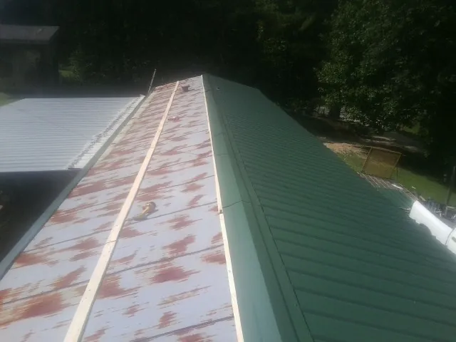 Old rusted panels beside newly installed green metal roofing — Wind Damage Roof Repair by Roofing Brothers in Shapleigh