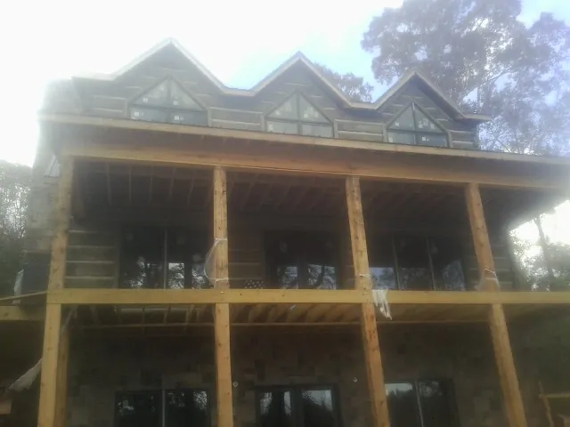 Dormers and porch framing on a large log home under construction — Roof Coating work by our crew in Shapleigh