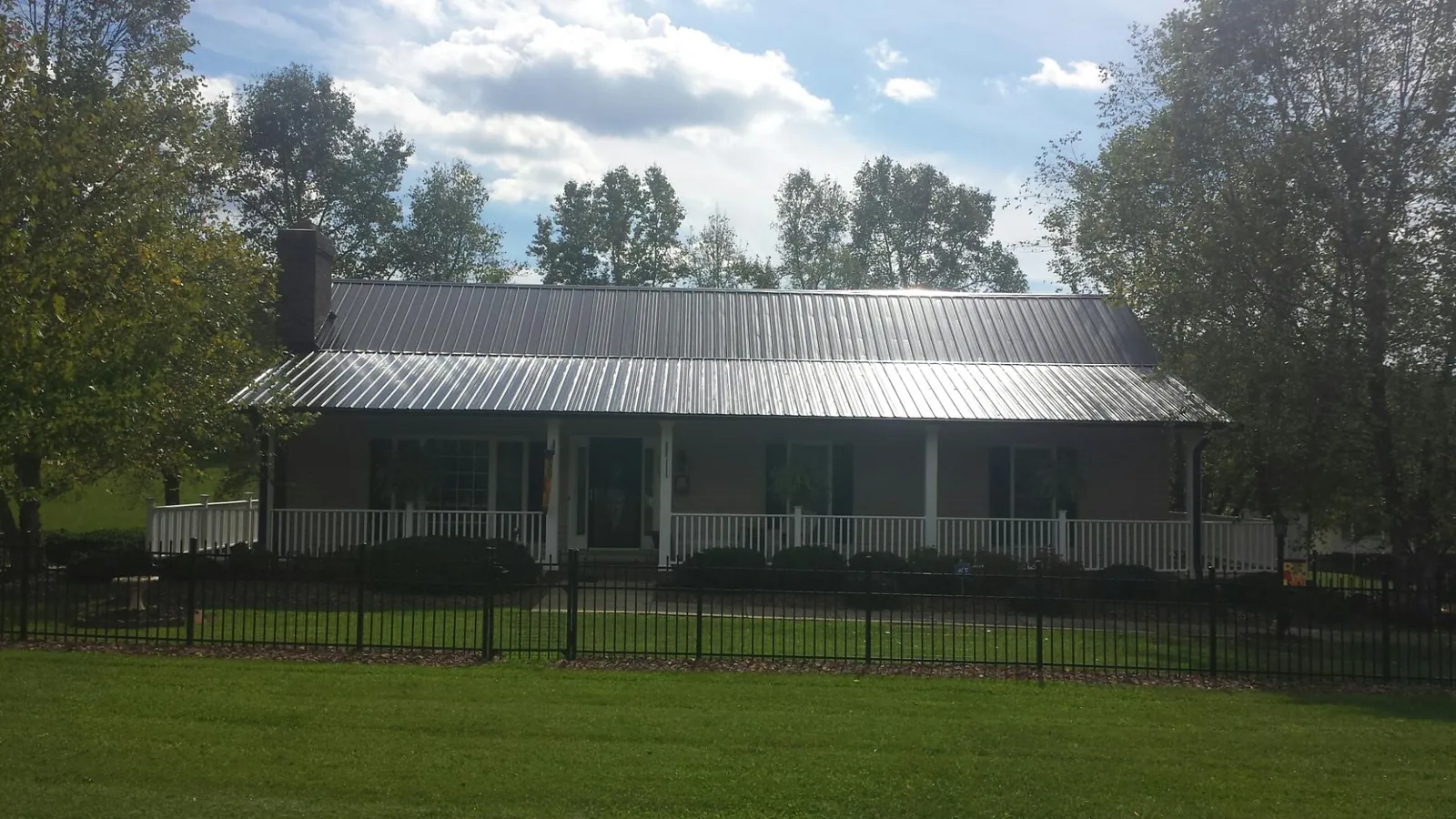 Gray metal roof on a brick ranch with a full width front porch — Gutter Guard Installation work by our crew in Shapleigh
