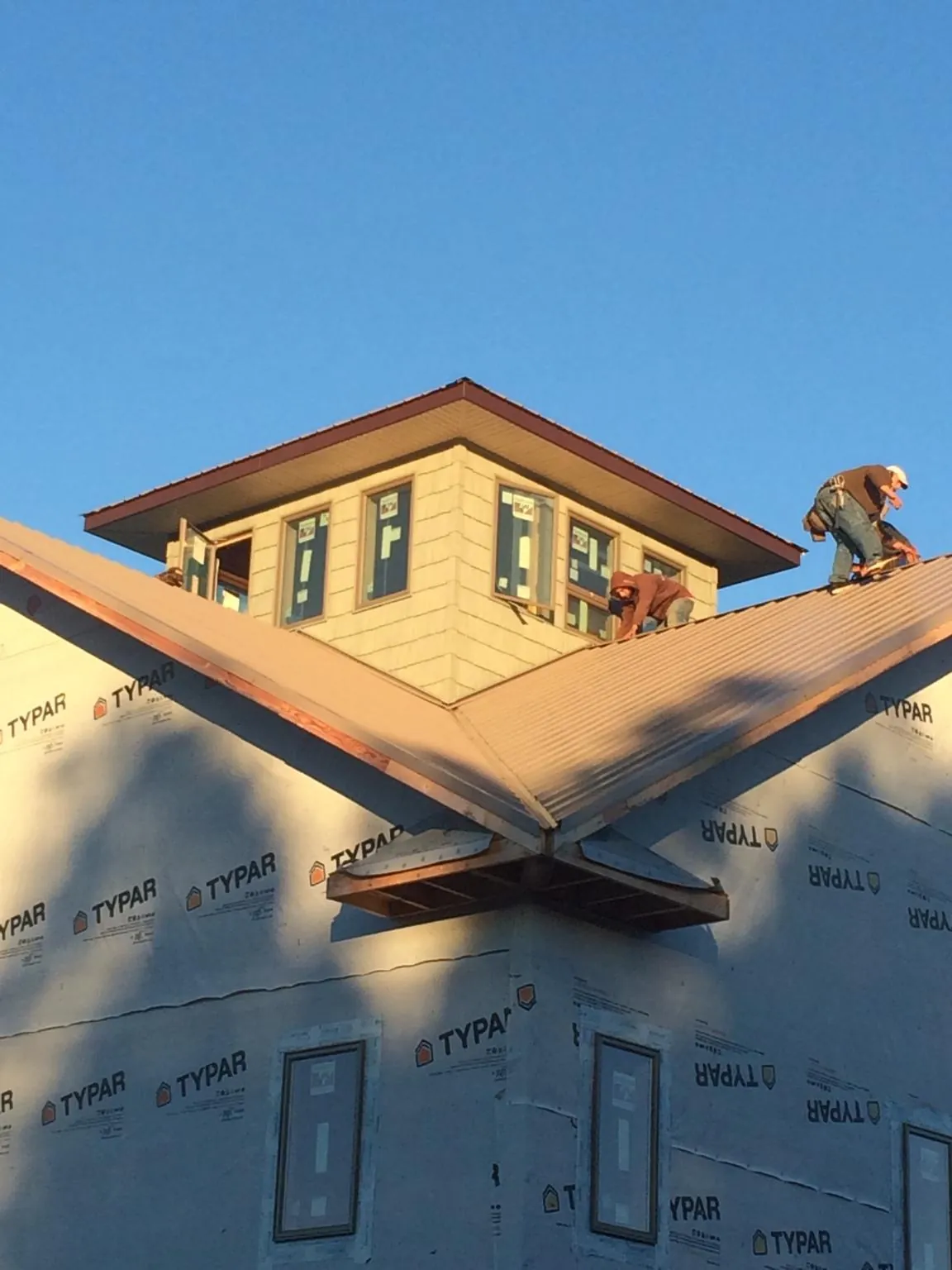 Roofers working around a rooftop cupola on a new metal roof at sunset — Roof Waterproofing in Shapleigh by Roofing Brothers